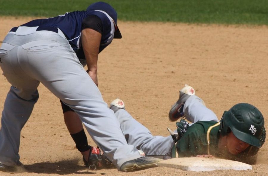 An MDI baseball player slides back into first base during a game at Presque Isle High School in 2017.