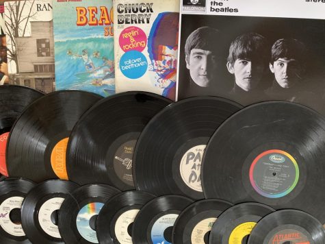 Record discs, as well as old record covers, are laid out across a table.